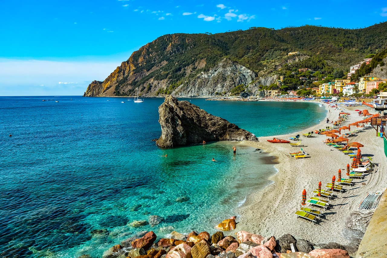 Breiter Sandstrand in Monterosso al Mare mit Sonnenschirmen, Badegästen und dem Ligurischen Meer im Hintergrund.