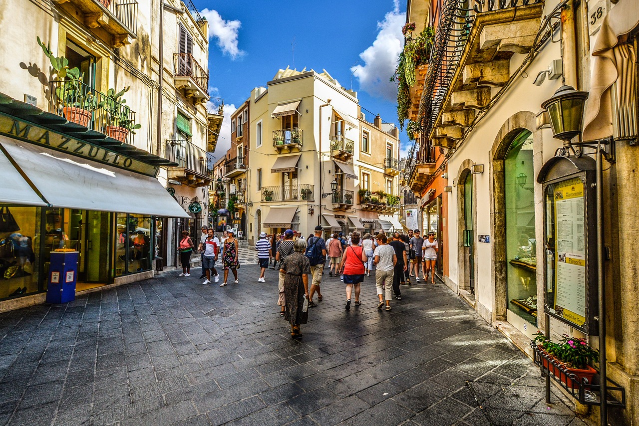 Belebte Innenstadt der Taormina mit vielen Touristen und Einheimischen in den engen Gassen der Altstadt an einem sonnigen Tag