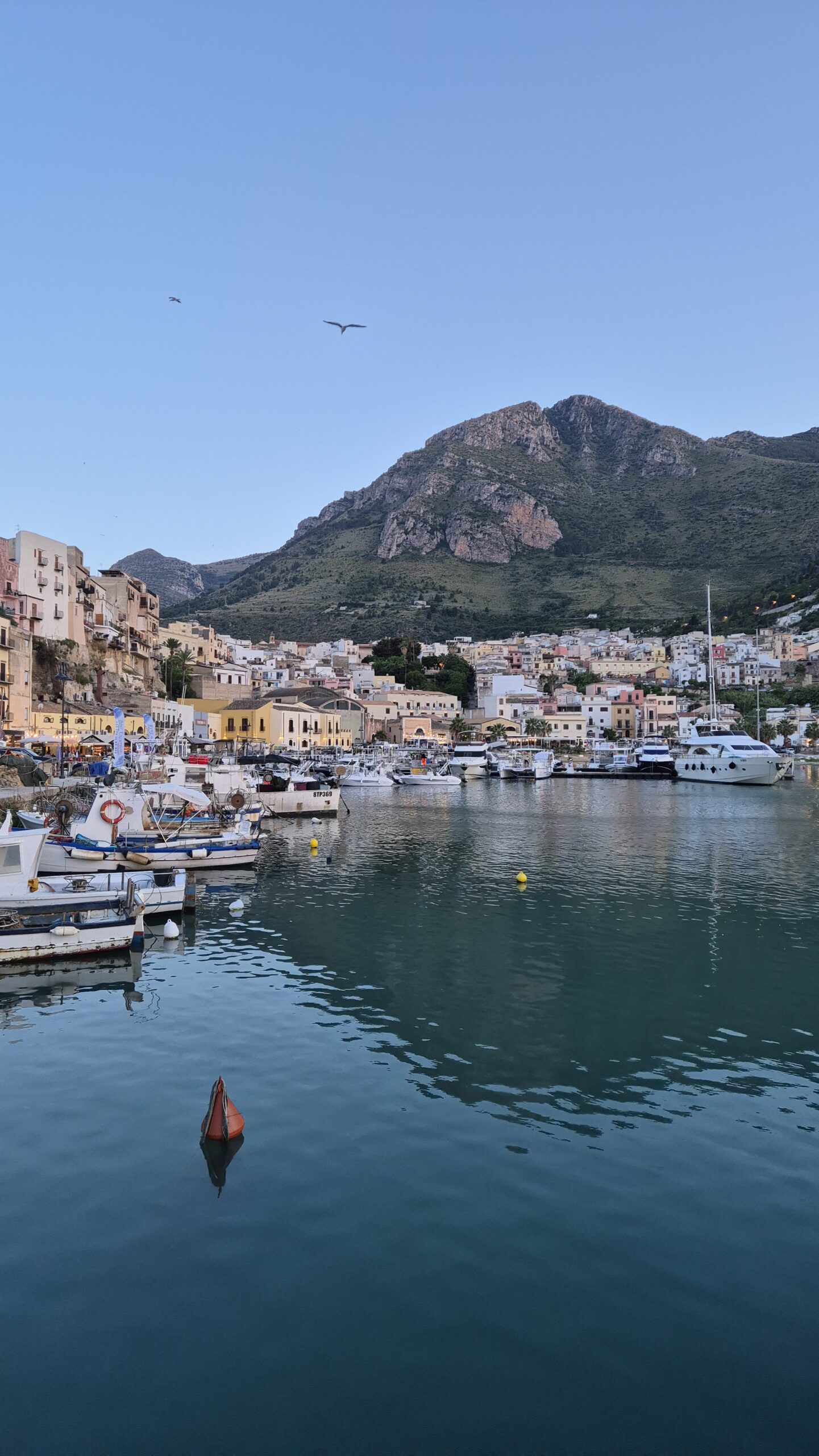 Hafen von Castellammare del Golfo bei Sonnenuntergang mit Booten und Bergen im Hintergrund an der sizilianischen Küste