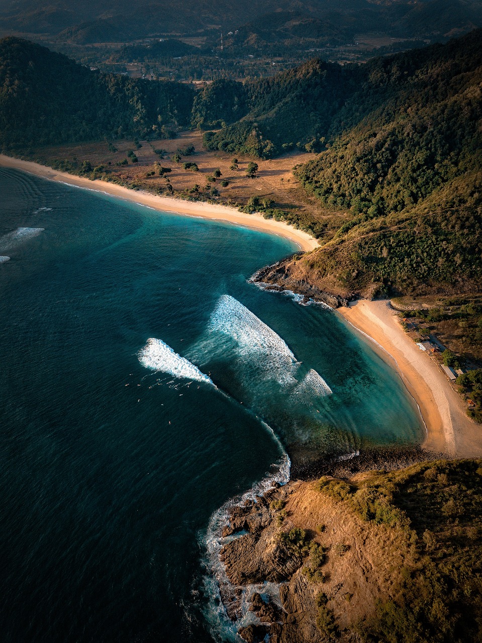 Drohnenaufnahme eines naturbelassenen Strandes im Parco Naturale della Maremma mit türkisblauem Meer, Pinienwald und unberührter Küstenlandschaft in der Toskana.