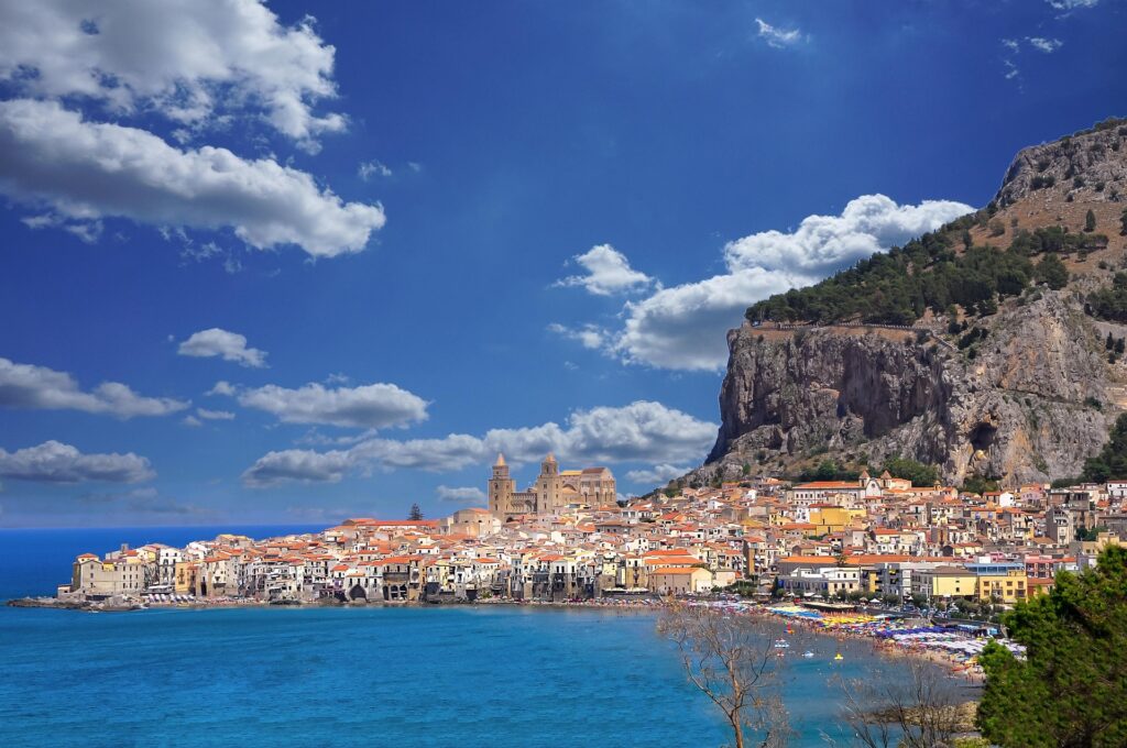 Panoramablick auf die Altstadt von Cefalù an der Nordküste Siziliens mit Strand, Kathedrale und markantem Felsen.