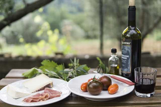 Italienische Antipasti mit Käse, luftgetrocknetem Schinken, Tomaten und Rotwein auf einem Tisch im Freien.