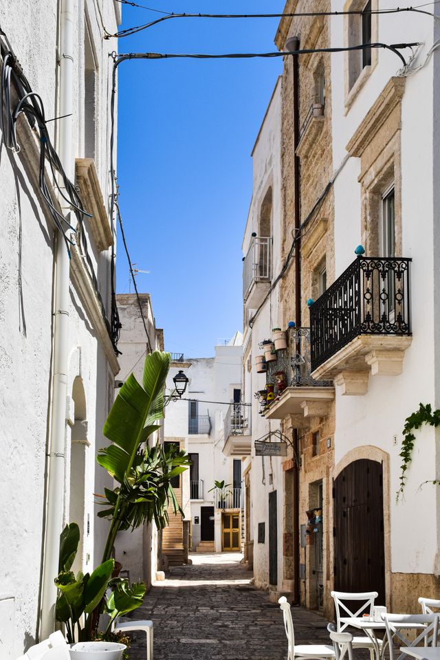 Malerische weiße Gasse mit historischen Häusern und Balkonen in der Altstadt von Locorotondo in Apulien, Italien.