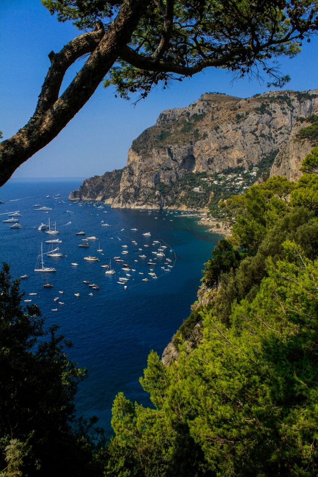 Traumhafte Küstenlandschaft auf Capri mit steilen Felsen, türkisblauem Meer und Segelbooten