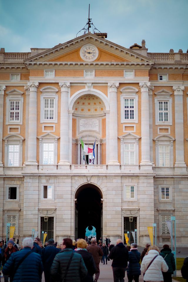 Hauptfassade des Königspalasts von Caserta mit klassizistischer Architektur und Besuchern vor dem Eingang in Kampanien, Italien.