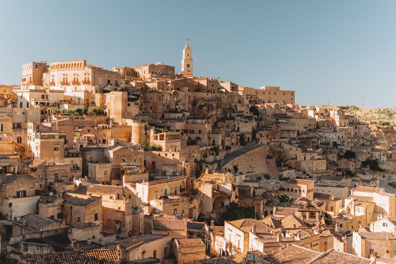 Gallipoli in Apulien mit Menschen im Wasser, blauem Meer und weißer Altstadt auf einer historischen Stadtmauer