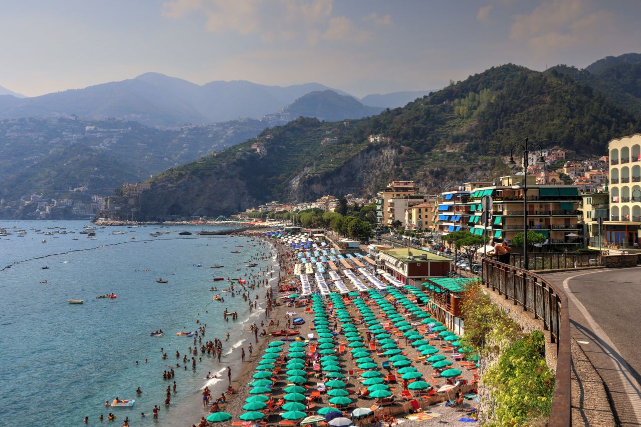 Spiaggia di Maiori mit bunten Sonnenschirmen, Badegästen und Blick auf die Berge der Amalfiküste